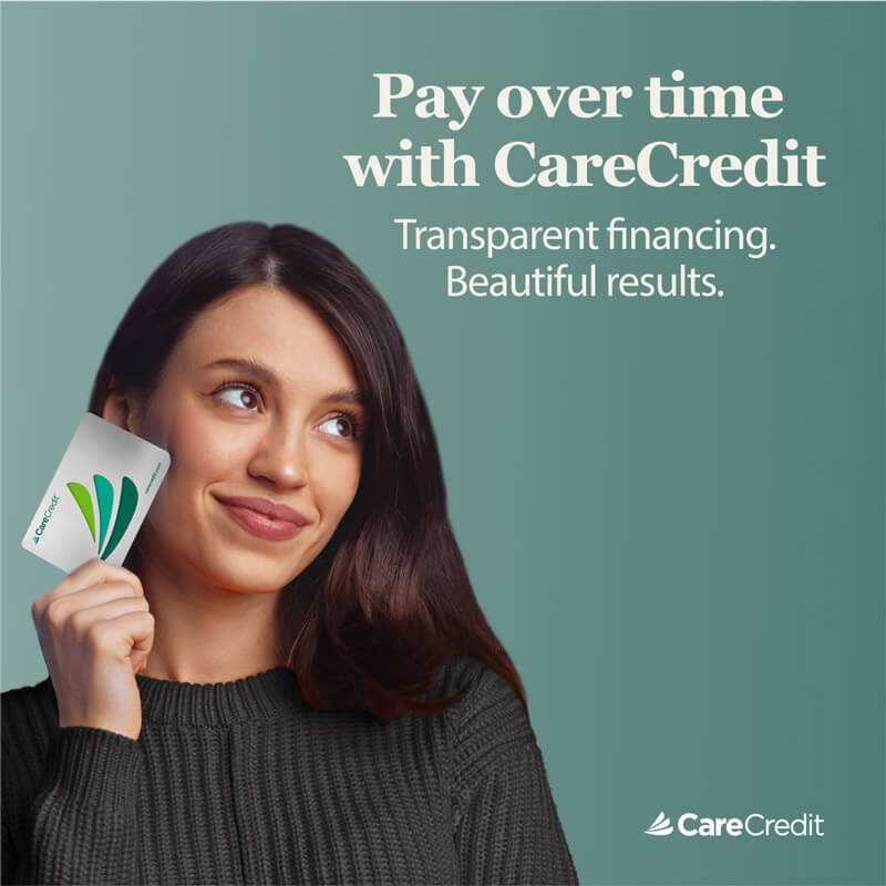 Woman smiling and holding up her CareCredit card